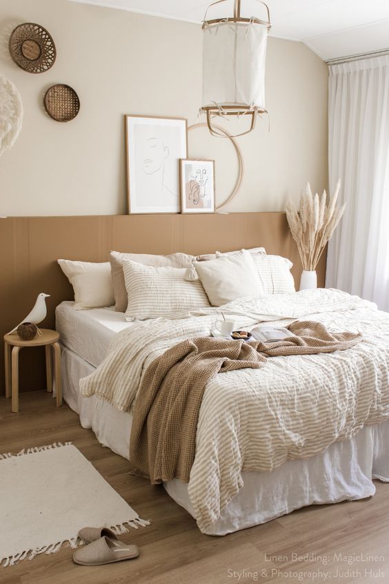 a neutral boho bedroom with a terracotta accent, a pendant lamp, woven baskets, layered bedding