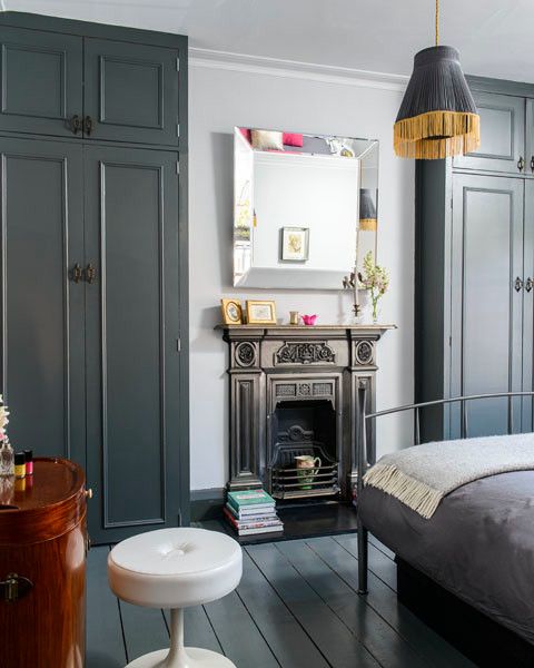 a laconic vintage bedroom in grey and white, with a fireplace, a pendant lamp with fringe and a metal bed