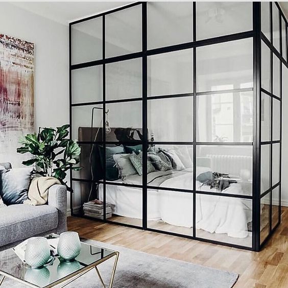 a laconic neutral bedroom with a dark bed, some neutral bedding is fully enclosed into glass to bring light to it