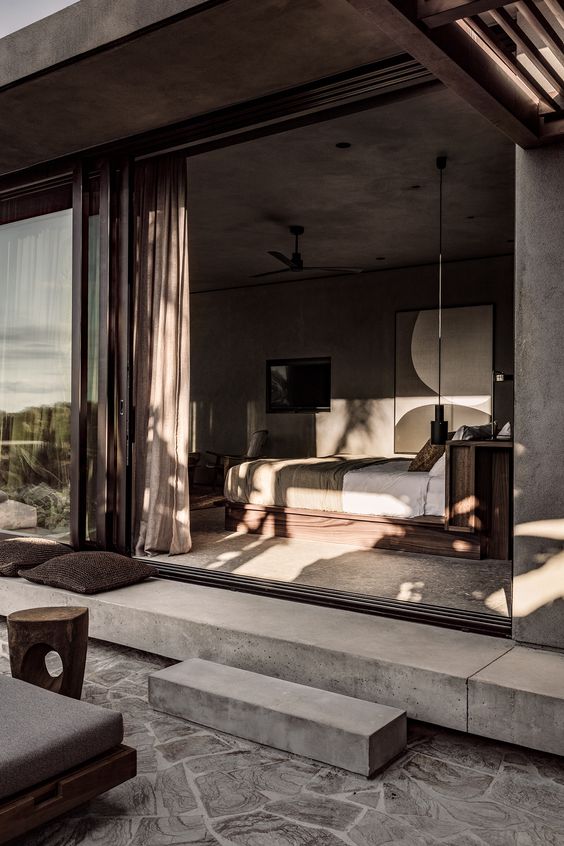 a contemporary bedroom in earthy tones, with statement art and a sliding glass door that leads to a terrace is a lovely room