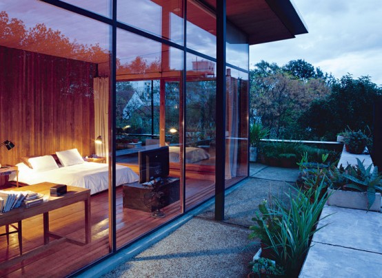 a stylish mid-century modern bedroom clad with plywood, with chic furniture, a sleeping and a working zone and glass walls to benefit from the views