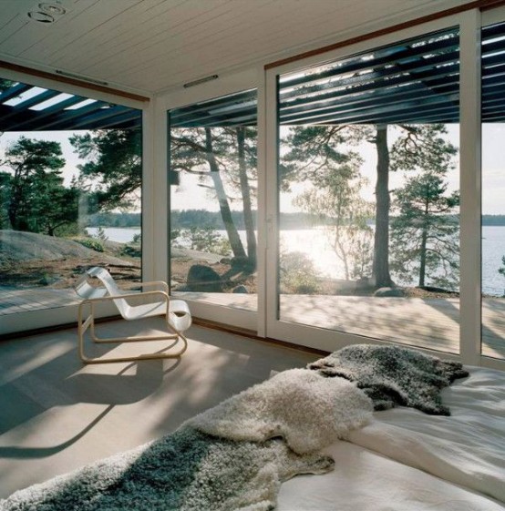 a neutral contemporary bedroom with stylish furniture, glass walls and an entrance to the terrace is filled with light and air