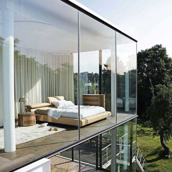 a contemporary bedroom with chic furniture, glass walls and a curtain that separates the bedroom from the rest of the space