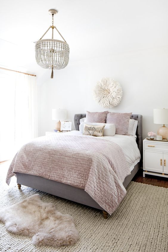 a cool girlish bedroom with a grey bed, pink and neutral bedding, a blush rug, a beaded chandelier and touches of gold