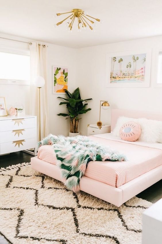 a tropical girlish bedroom with a pink floating bed, a printed rug and bedding, bold artworks and touches of gold