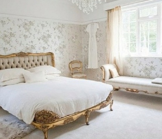 a neutral feminine bedroom with floral wallpaper walls, exquisite furniture with gold touches and a crystal chandelier