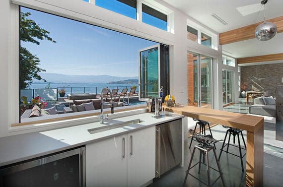 modern kitchen design with panorama window along the worktop, breakfast bar as a separating element to the living room and under-unit refrigerator and freezer