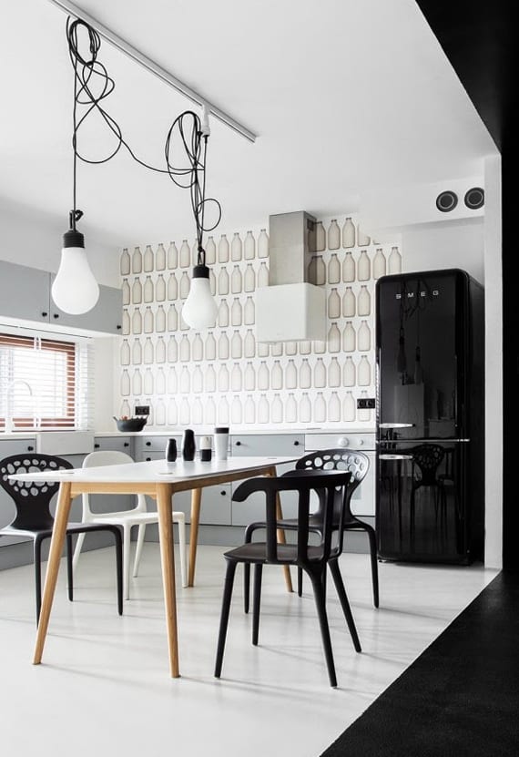 the kitchen in black and white with a retro black refrigerator, wallpaper with milk bottles, light gray kitchen cabinets, and wooden dining table with black dining chairs_cool kitchen wall design with wallpaper and black wall paint