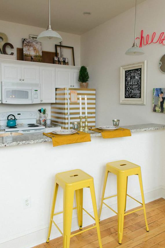 small white kitchen with bar counter, yellow bar stools, white wooden kitchen cabinets and diy retro refrigerator with striped pattern in gold and white